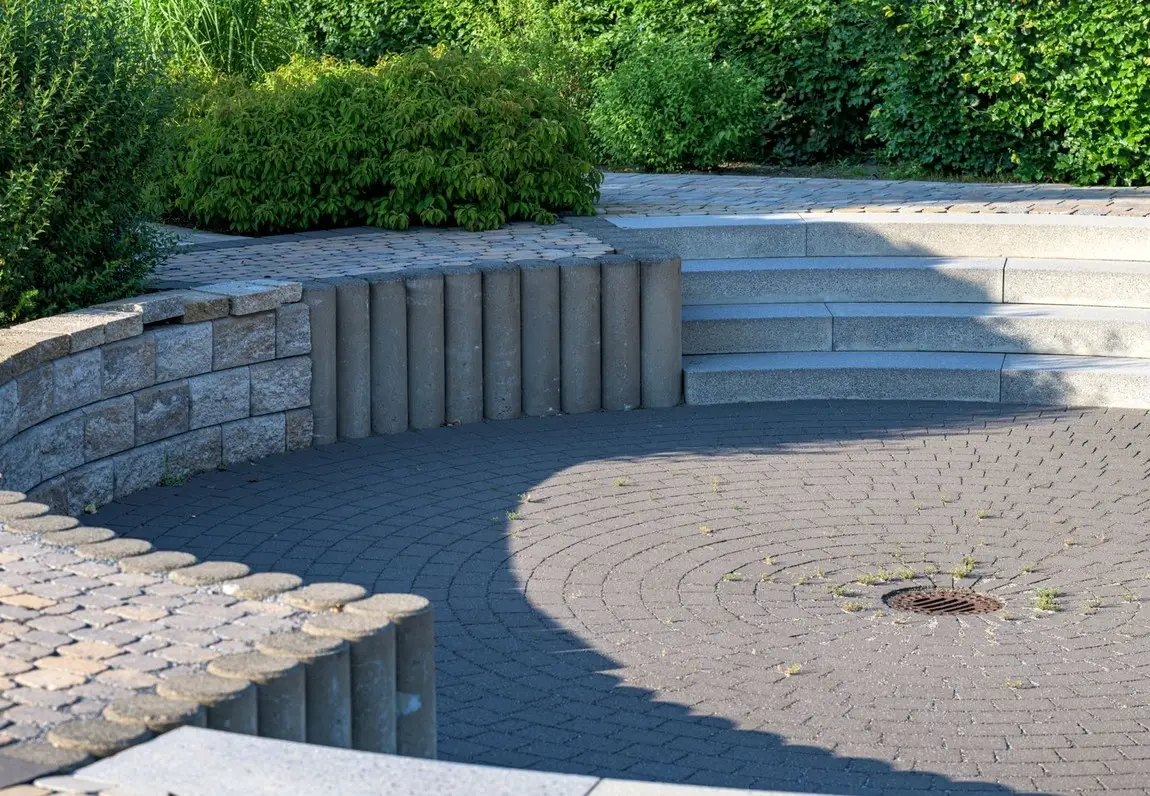 A circular paved terrace with curved stone retaining walls and wide steps.